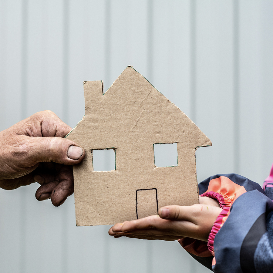 A person holding a cardboard house in their hands.