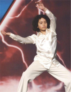 A young man in white shirt and pants performing dance moves.