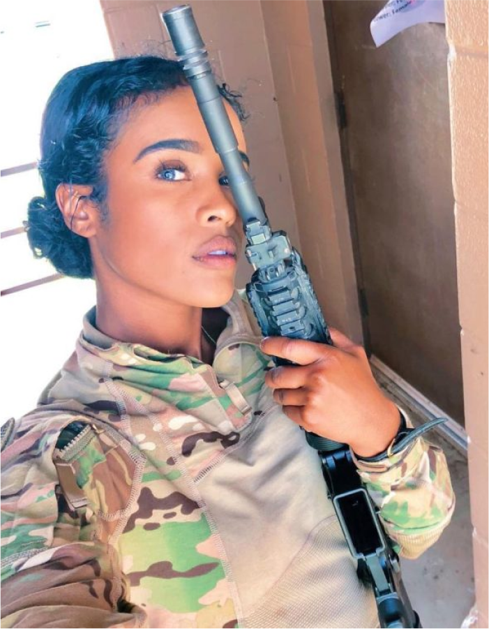 A woman in camouflage holding a gun.